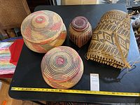 Top view showing all four baskets including two coiled lidded baskets, the ethnic woven strap basket, and the smaller reddish basket