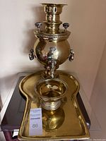 Full view of brass samovar centered on brass tray, showing reflective, polished surface and overall shape