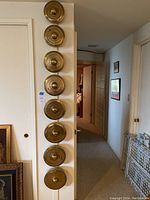 Eight brass discs mounted vertically on a white wall