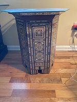 Front view of hexagonal table showing full inlaid panel and glass top