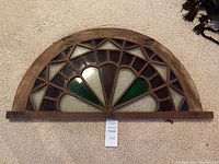 Full view of half-circle transom window showing wood frame and colored glass sections in red, green, blue, and amber colors.