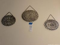Three oval decorative metal framed hanging mirrors displayed on wall