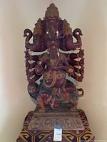 Front view showing all four Ganesh heads, multiple arms and carved base
