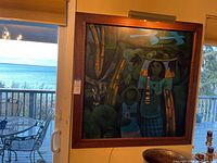 Full frontal view of the framed painting hung above a table with balcony view in background