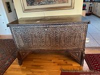 Full front view of chest on stand showing inlaid geometric patterns and drop-front panel