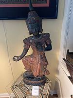 Full view of the Thai wooden Buddha statue showing its overall posture and intricate mirror decorations.