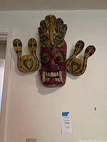 Large cobra-adorned mask mounted on wall, two snake side pieces visible.