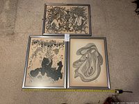 Three framed vintage black and white prints laid together showing detailed line work and figures, with tape measure for size reference approximately 19x26 inches