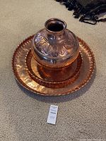 Three-piece set of vintage hammered copperware including two large platters and one urn.
