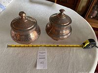 Two Turkish copper tinned covered jars side by side on a table with measuring tape showing length approximately 12 inches across both jars.