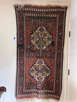 Full view of the vintage Kilim style textile hung on the wall with multiple attached jewelry items.