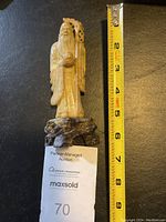 Front view of carved soapstone statue standing approximately 6 inches tall next to a measuring tape for scale.