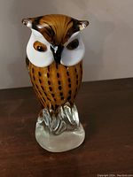 Front view of solid blown glass owl figurine showing detailed colored spots and prominent white face and amber eyes.
