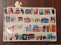 Front side of Kate Spade bookshelf print pencil case with gold trumpet zipper pull on wooden background.
