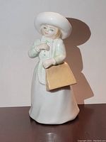Front view of the Royal Doulton figurine showing the girl in white dress and hat holding a yellow handbag.