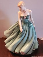 Front view of the Royal Doulton Sarah figurine showing the full front of the green flowing dress and the rose detail at the bodice.
