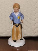 Front view of the Royal Doulton Childhood Days figurine depicting a young boy sheriff with star badge and holstered pistols.