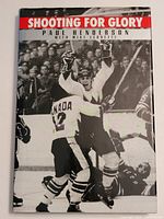 Front cover of the signed 'Shooting for Glory' hardcover book showing hockey scene in black and white with players celebrating and playing.