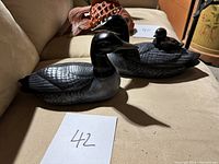 Photo showing two adult black ceramic loons with finely textured feather details, sitting side by side on a beige surface.