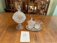 Full view of the large candy jar with lid and the miniature sugar bowl, creamer, and tray set on a table.