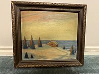 Framed oil on board painting showing a coastal landscape with a small house and trees against a sea backdrop.