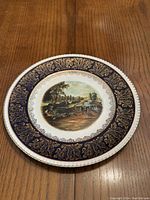 Full view of the plate showing the detailed English countryside scene in the center and the ornate dark blue and gold border.