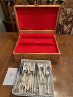 Wooden cutlery box open showing red velvet lining with slots and cutlery set laid out