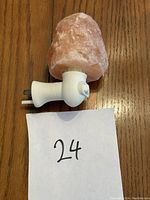 Photo of a pink Himalayan salt rock light with a white plug-in base on a wooden surface, alongside a paper with number '24'