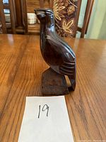 Full front view of the solid wood eagle carving detailing the polished wood surface and the base on a wooden table.