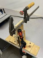 Side view of the manual bar clamp showing wooden handle, metal bar, and wooden base