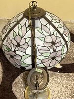 Top view of the stained glass dome lamp showing floral pattern and brass hanging fixture with chain and plug cord.