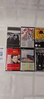 Eight cassette tapes arranged in two rows of four, showing album artwork and titles where visible.