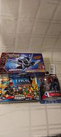 Photo showing the Guardians of the Galaxy spaceship set box, Thor action figure box, and Black Widow figure in packaging all arranged on a white surface.