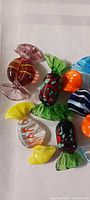 Close-up view of several Murano style glass candies in various colors including red, green, yellow, and black patterns.