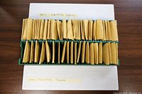 Two green plastic trays filled with paper coin flips each containing a single colonial token