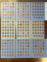 Three blue coin albums arranged together showing multiple Lincoln Head pennies from different years inserted in the albums by year.