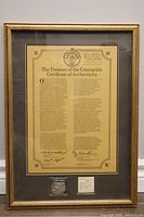 Full view of gold-tone frame holding certificate and coin