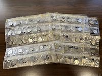 Several coin storage sheets filled with Canadian nickels from various years between 1921 and 1945 laid flat on a wooden surface.