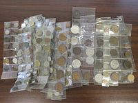 Multiple plastic sheets with vintage coins in individual pockets arranged on a surface.