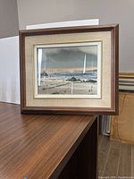 First watercolour painting of calm seascape in frame on table.