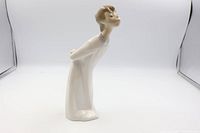 Side view of Lladro kissing boy figurine, highlighting posture and glossy finish.