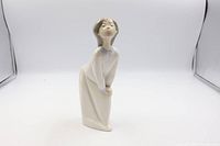 Front view of the Lladro figurine showing girl bending forward with puckered lips.
