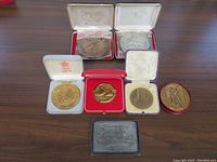 Overall view of seven medals and plaques showing various cases and medals including a large Victory Medal and smaller medals in cases.