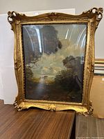 Full view of oil painting with ornate gold frame showing landscape scene under glass