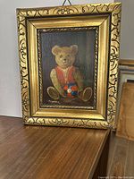 Front view of the small framed oil painting of a teddy bear holding a ball.