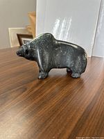 Side view of hand carved musk ox figurine on wood surface.