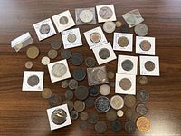 Overview of all assorted coins, tokens and medal laid out on wooden table