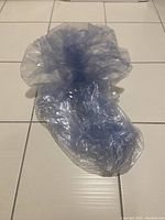 Deflated clear blue inflatable chair shown flat on tiled floor, giving view of the entire uninflated item.