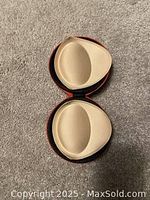 View of beige cup inserts placed side by side in an open clamshell case with black lining showing shape and surface detail