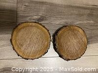 Top view of two glazed wood rounds showing smooth surfaces and natural bark edges on a wooden floor.